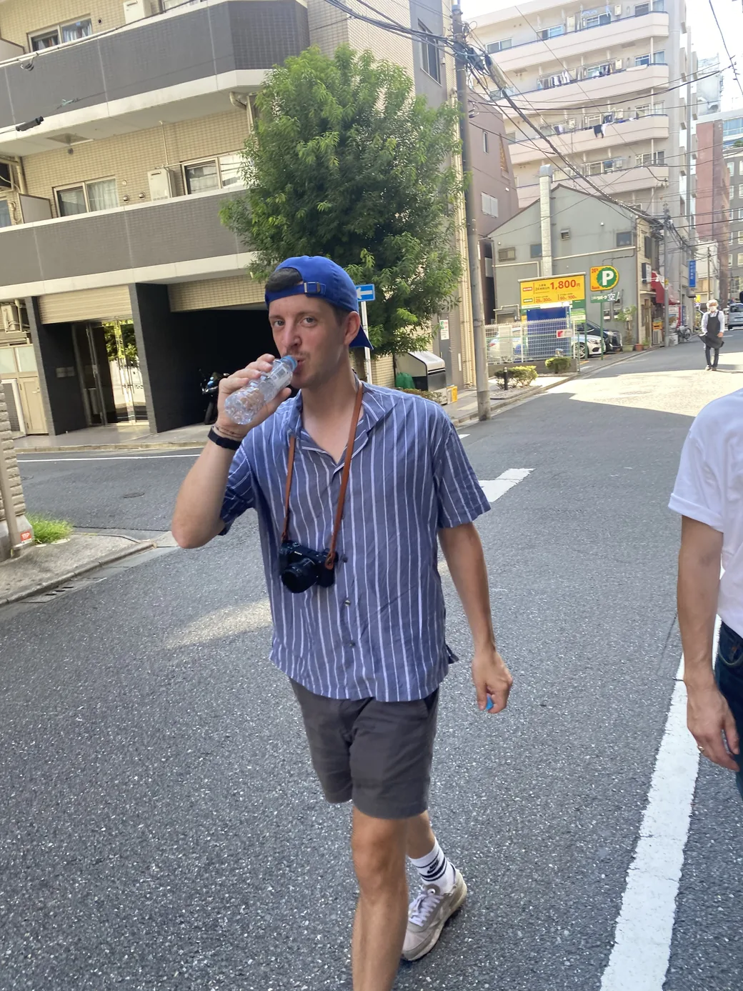 Erwan on a street in Tokyo, drinking from a water bottle